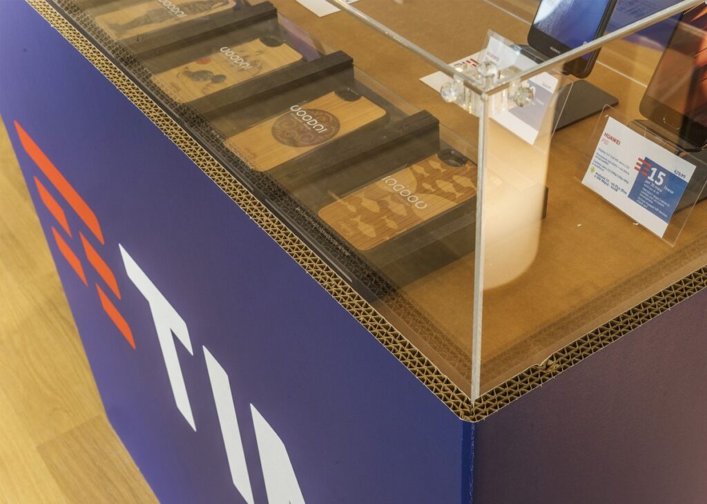 Comptoir modulable en carton recyclé pour l’aménagement de magasins, avec plateaux personnalisés imprimés et poignées métalliques, intégré dans une structure décorative aux lignes épurées et couleurs vives (bleu et motifs géométriques). Idéal pour organiser des espaces commerciaux ou événementiels - Le Meuble en Carton une marque du groupe Natur Design