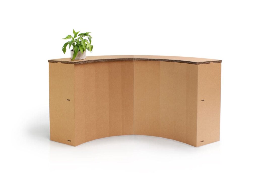 Banque d'accueil en carton écoresponsable pour stands événementiels et magasins, conçue avec des panneaux structurés en cartons épais pour une esthétique chaleureuse et durable. Idéale pour l’aménagement de points d’accueil dans les salons professionnels ou espaces commerciaux, elle intègre un plateau décoratif en carton recyclé et un plan incliné pratique pour faciliter le passage - Le Meuble en Carton une marque du groupe Natur Design