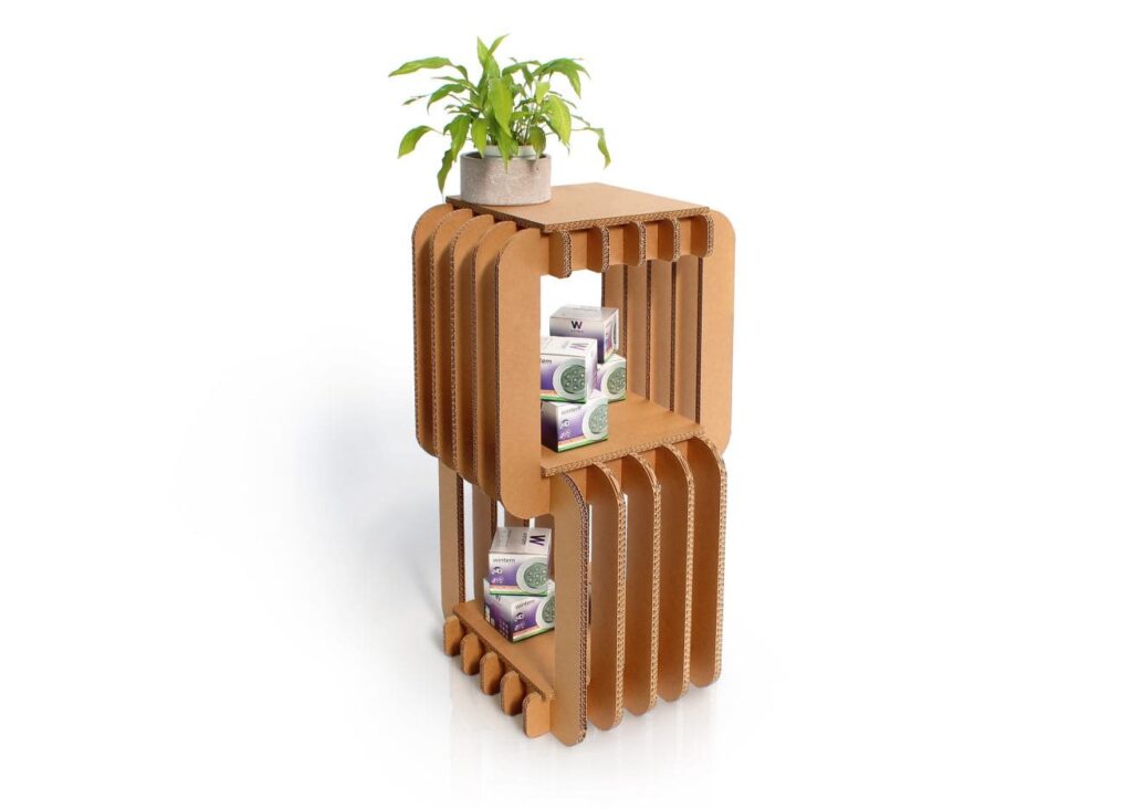 Étagère en carton design et fonctionnelle pour présentation de produits, idéale pour les espaces professionnels ou commerciaux. Structure solide en panneaux cartonnés avec poignées métalliques intégrées, contenant des boîtes de produits (ex : savons ou cosmétiques) et un petit pot de fleurs pour un décor naturel et esthétique - Le Meuble en Carton une marque du groupe Natur Design