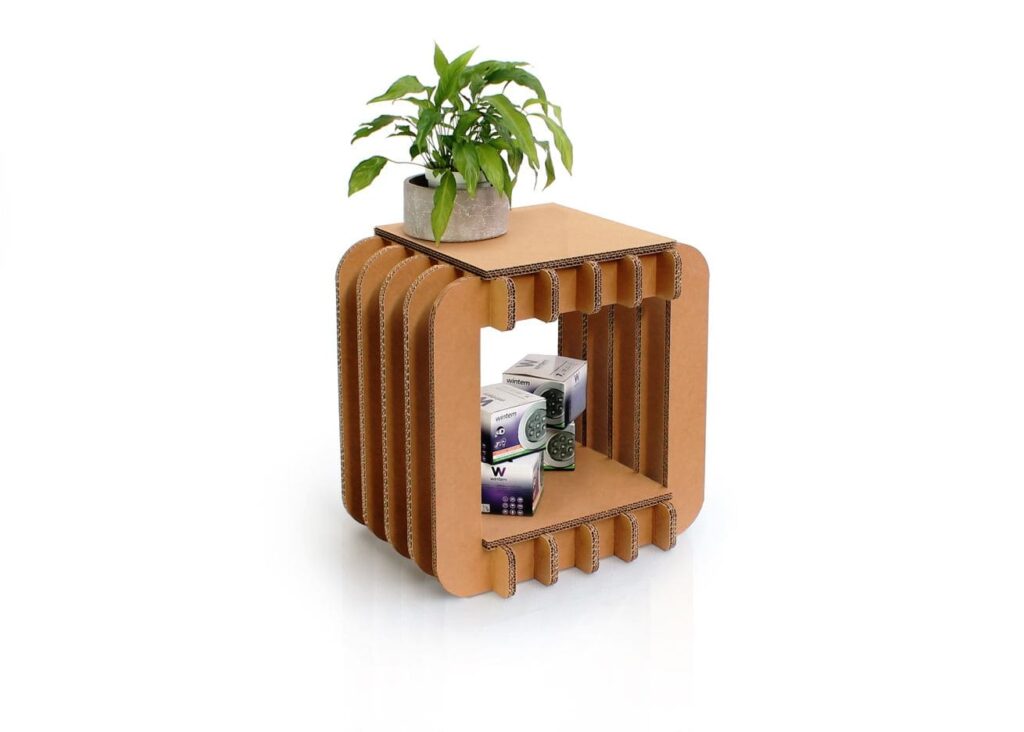 Étagère en carton MINTO avec plateau supérieur et compartiments ouverts pour rangement d'articles, idéale pour les espaces professionnels ou bureautiques. Visible sur l'image : présentation de produits cartonnés (ex. boîtes écologiques) et d'une plante verte dans un pot, mettant en valeur son design épuré et fonctionnel - Le Meuble en Carton une marque du groupe Natur Design