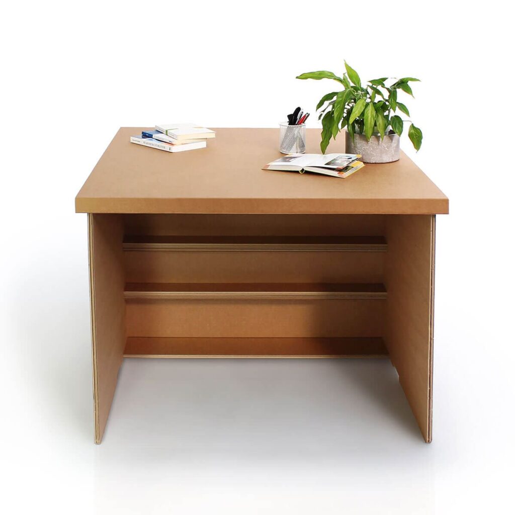 Extension banc d'accueil PMR en carton écologique, conçue pour les espaces professionnels et les points d'accueil avec plateau solide et rangements intégrés en haut du meuble. Idéale pour les halls d'accueil, caisses de distribution ou points d’accueil accessibles, combinée à une touche naturelle par la présence d’un vase avec plante verte et documents administratifs sur le plateau - Le Meuble en Carton une marque du groupe Natur Design